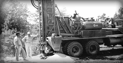 An early Flynn Drilling rig on a job with two crew members