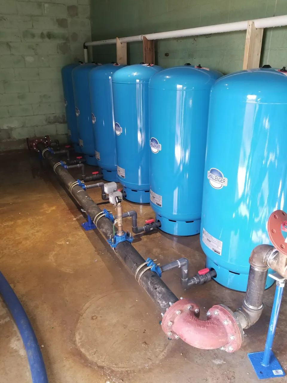 A bank of blue pressure tanks in a commercial pump house installed by Flynn Drilling
