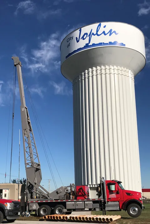 A Flynn crane truck working beneath the City of Joplin water tower