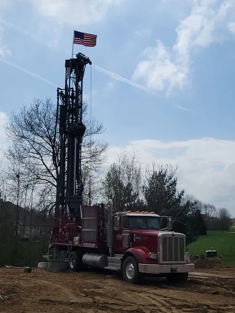A Flynn drill rig with its mast up beside a new home