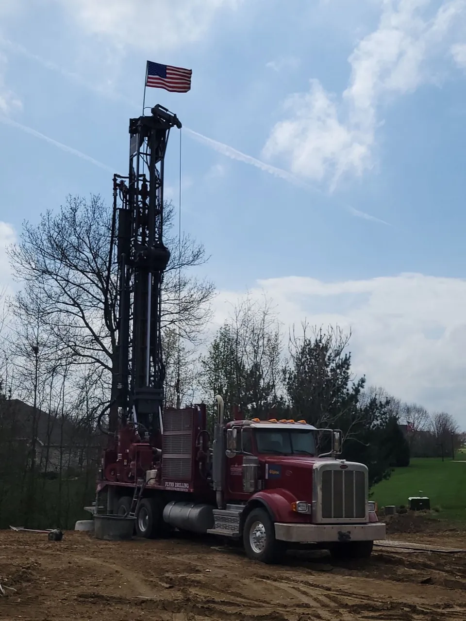 A Flynn Drilling rig with the mast raised and the flag flying on a Missouri job site